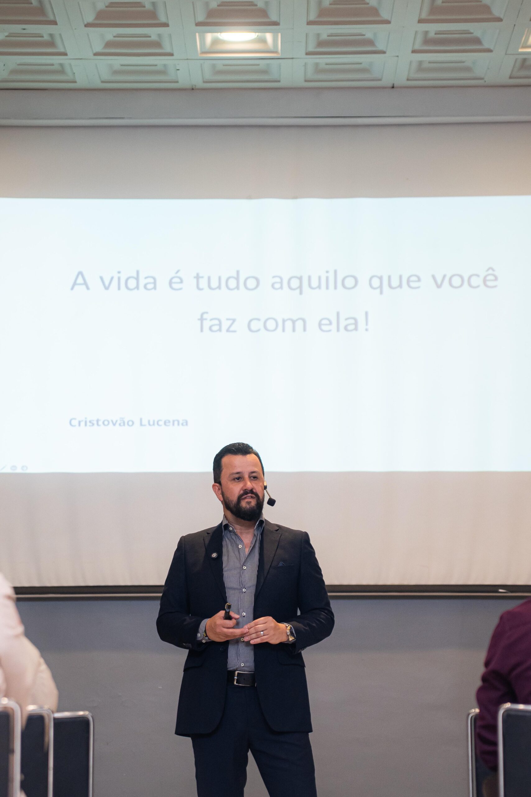 Cristovão Lucena no palco com slide motivacional ao fundo